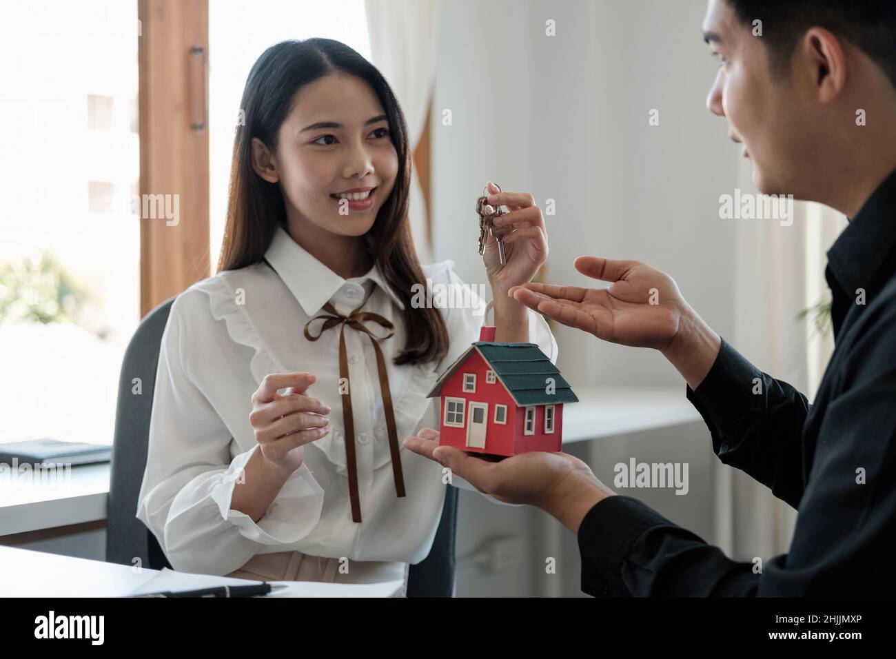 Agente immobiliare sta spiegando lo stile della casa ai clienti che vengono a contatto per vedere il disegno della casa e l'accordo di acquisto Foto Stock