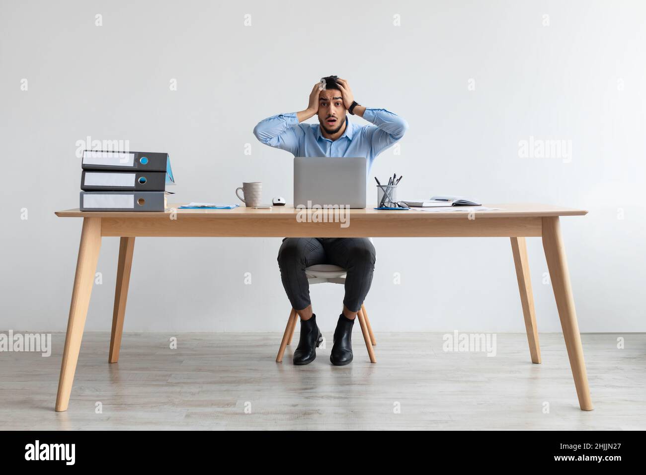 Scioccato ragazzo arabo afferrare la testa utilizzando il portatile Foto Stock