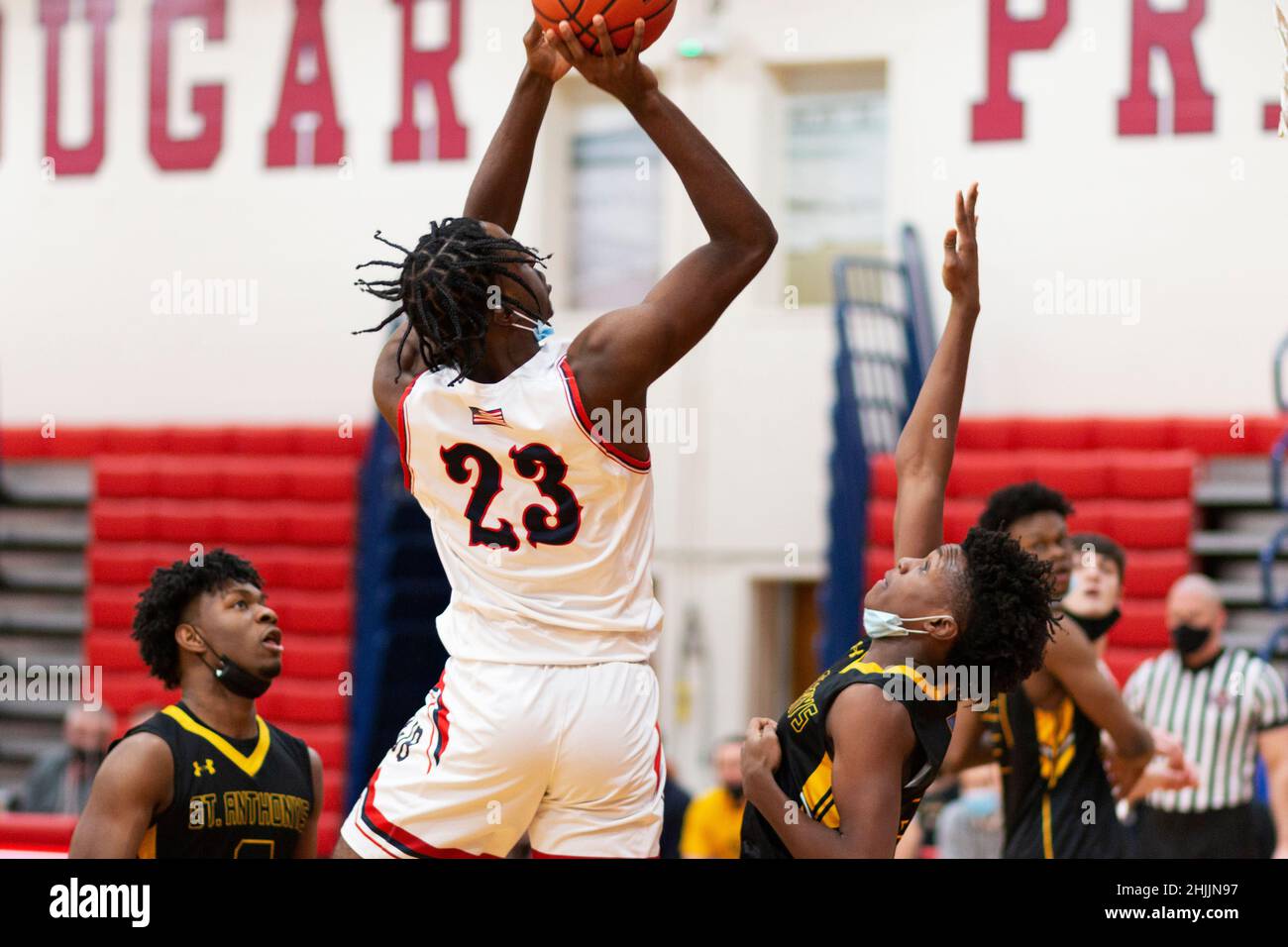 West Islip, New York, USA - 21 Gennaio 2022: Giocatore di basket delle scuole superiori che spara la palla sopra i difensori indossando maschere sotto i loro chins d Foto Stock