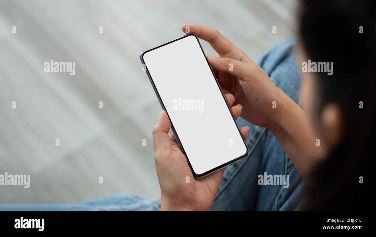 Donna che tiene uno smartphone con sfondo sfocato. Per montaggio display grafico Foto Stock