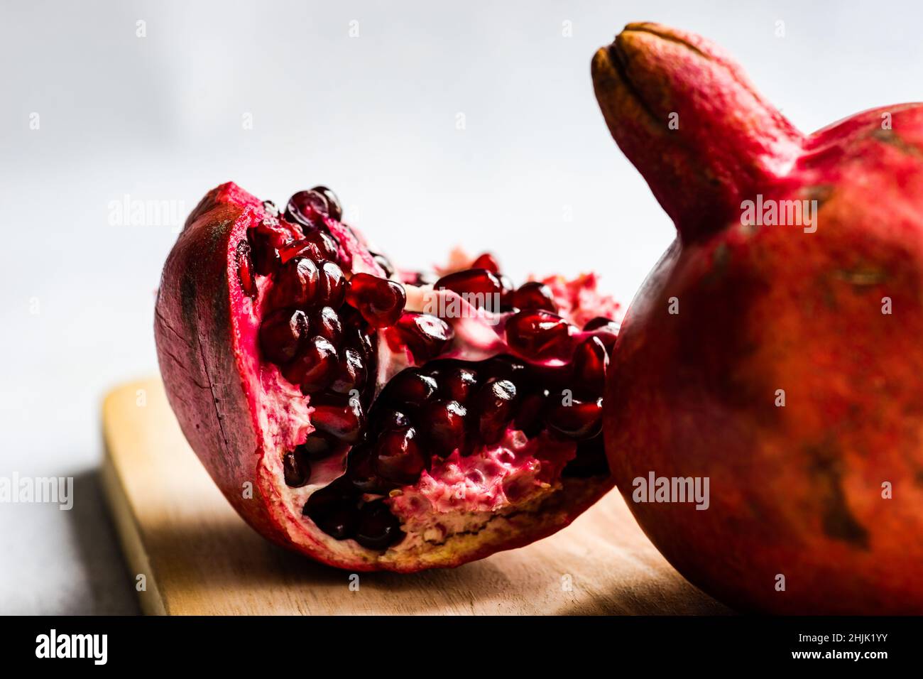 Primo piano di un segmento di melograno e melograno su un tagliere di legno Foto Stock