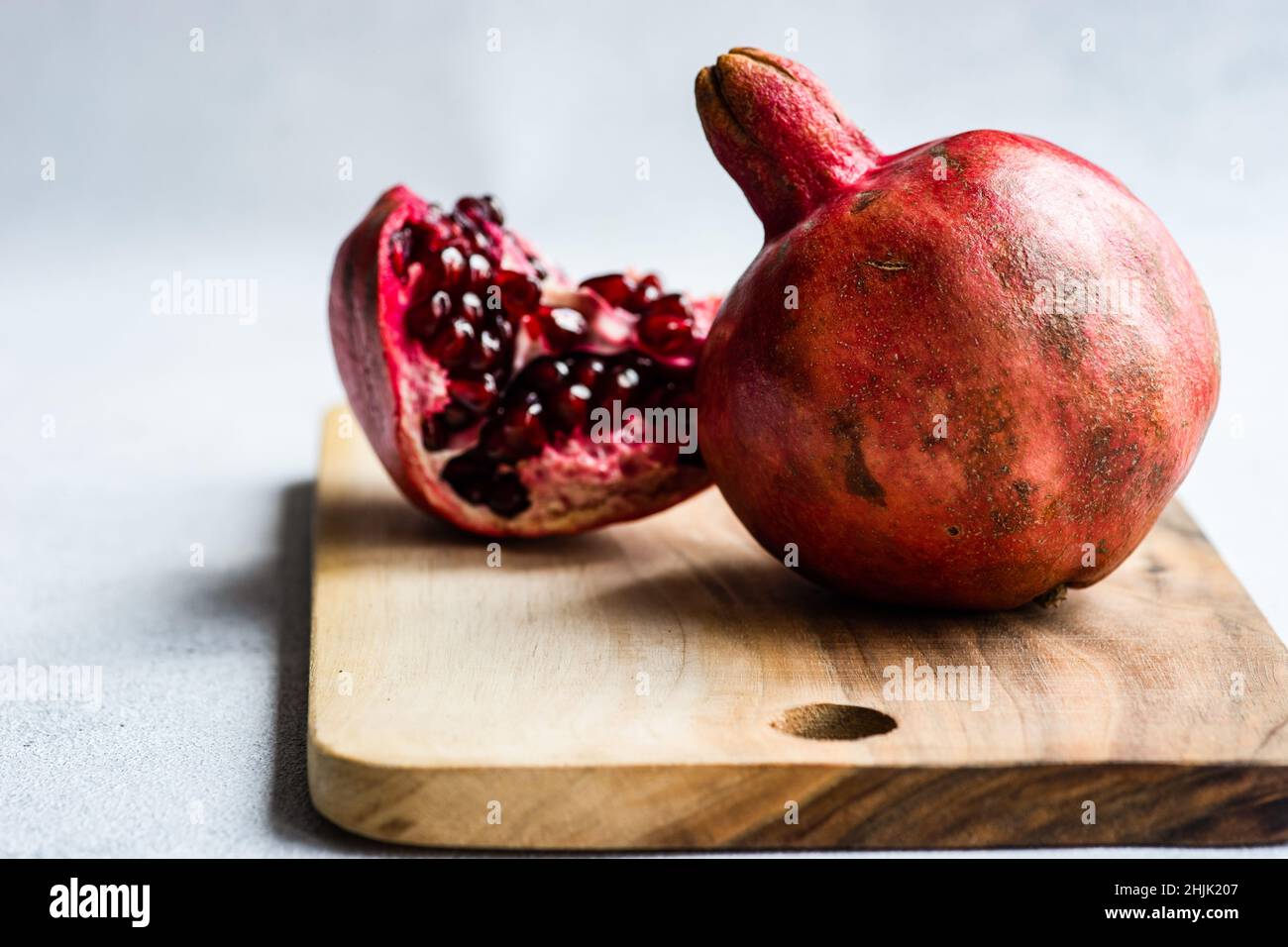 Primo piano di un segmento di melograno e melograno su un tagliere di legno Foto Stock