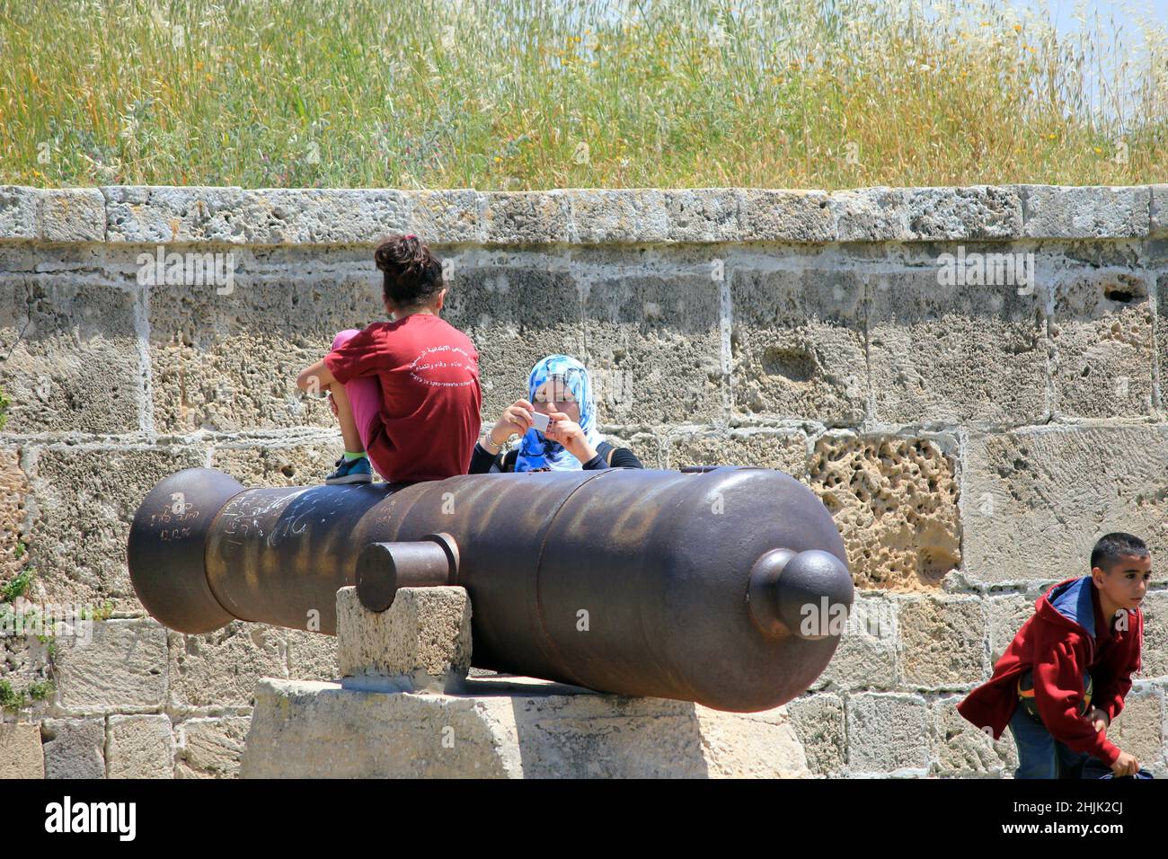 ACRO, ISRAELE - 12 MAGGIO 2011: Turisti non identificati sono fotografati ad uno dei cannoni sul pozzo della fortezza. Foto Stock