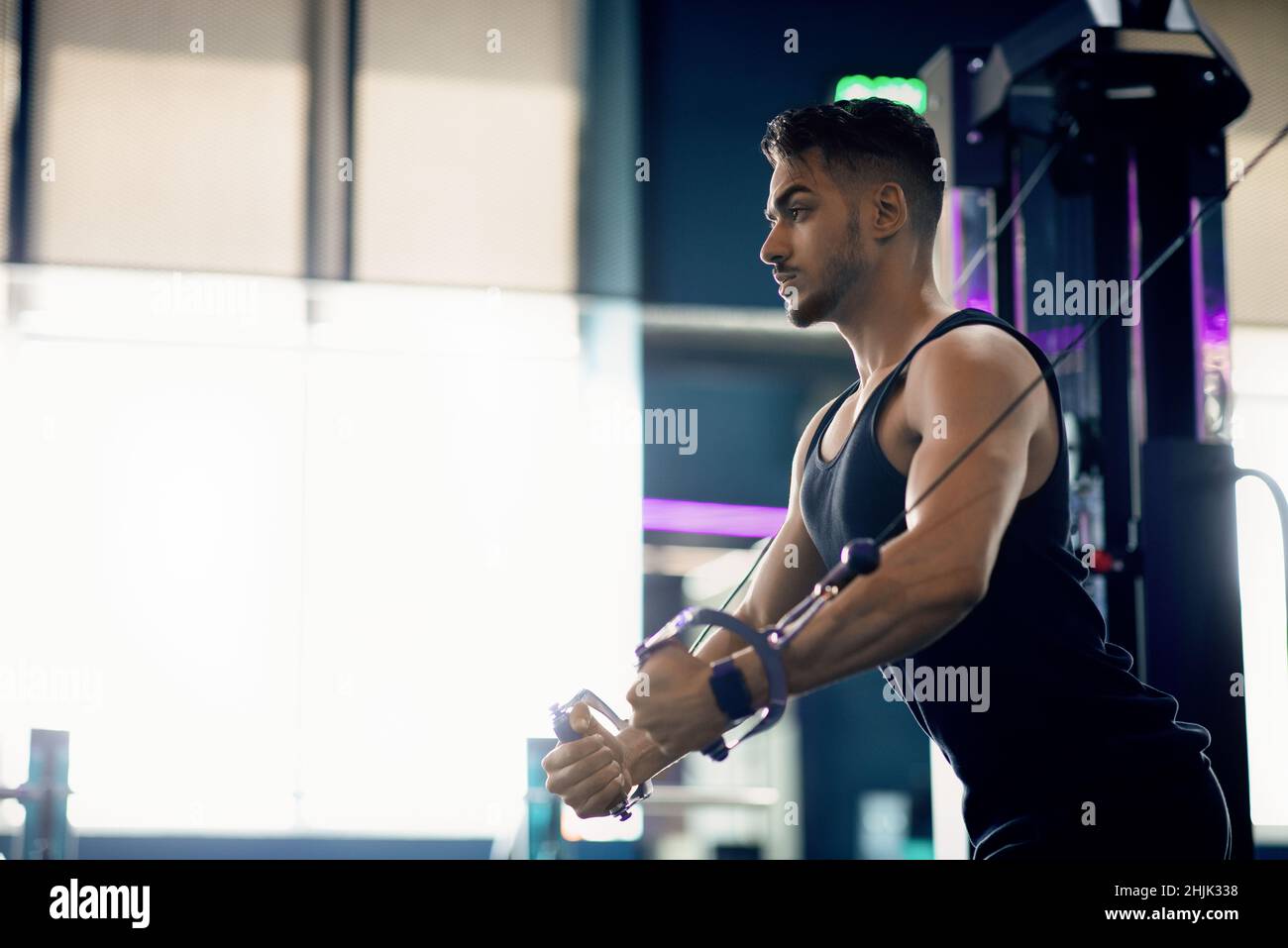 Fidato Muscular Arab Man Training con Crossover Machine alla moderna palestra Foto Stock