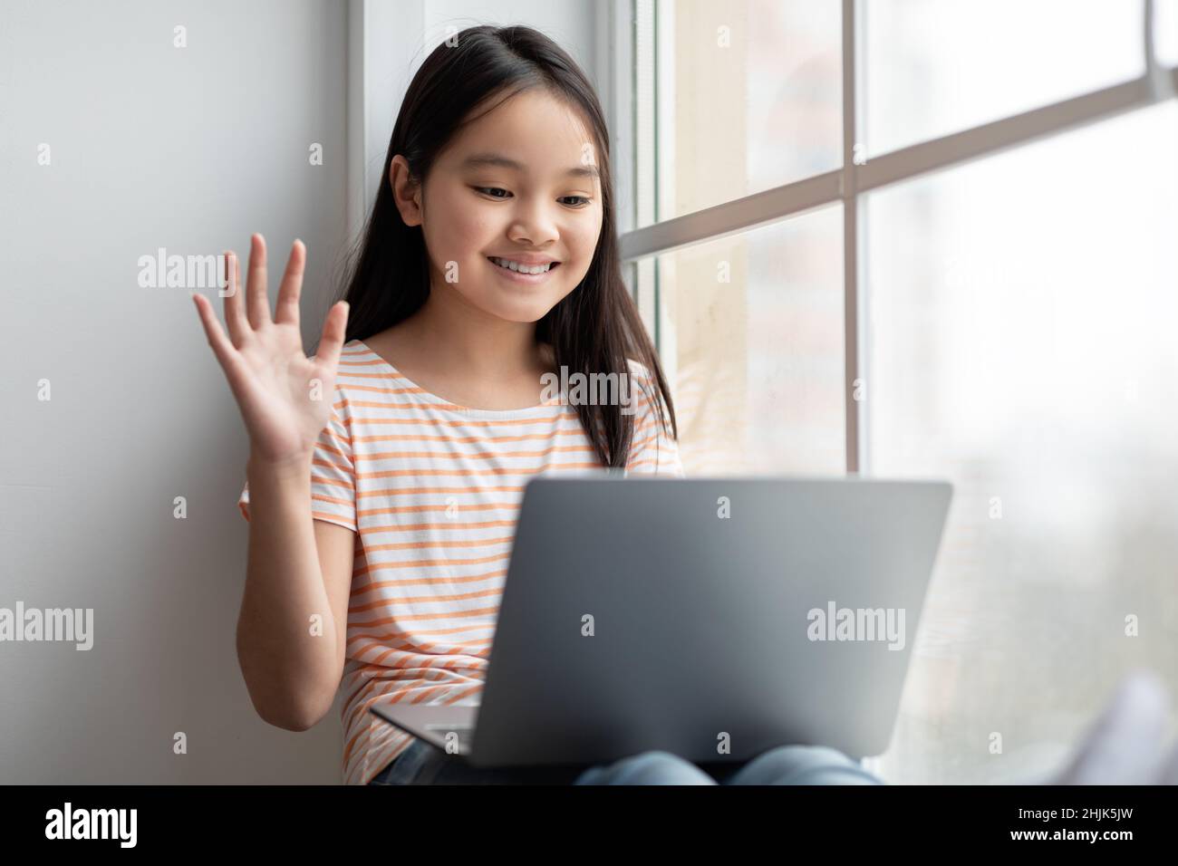 Ragazza asiatica carina adolescente che ha videochiamata, usando il laptop Foto Stock