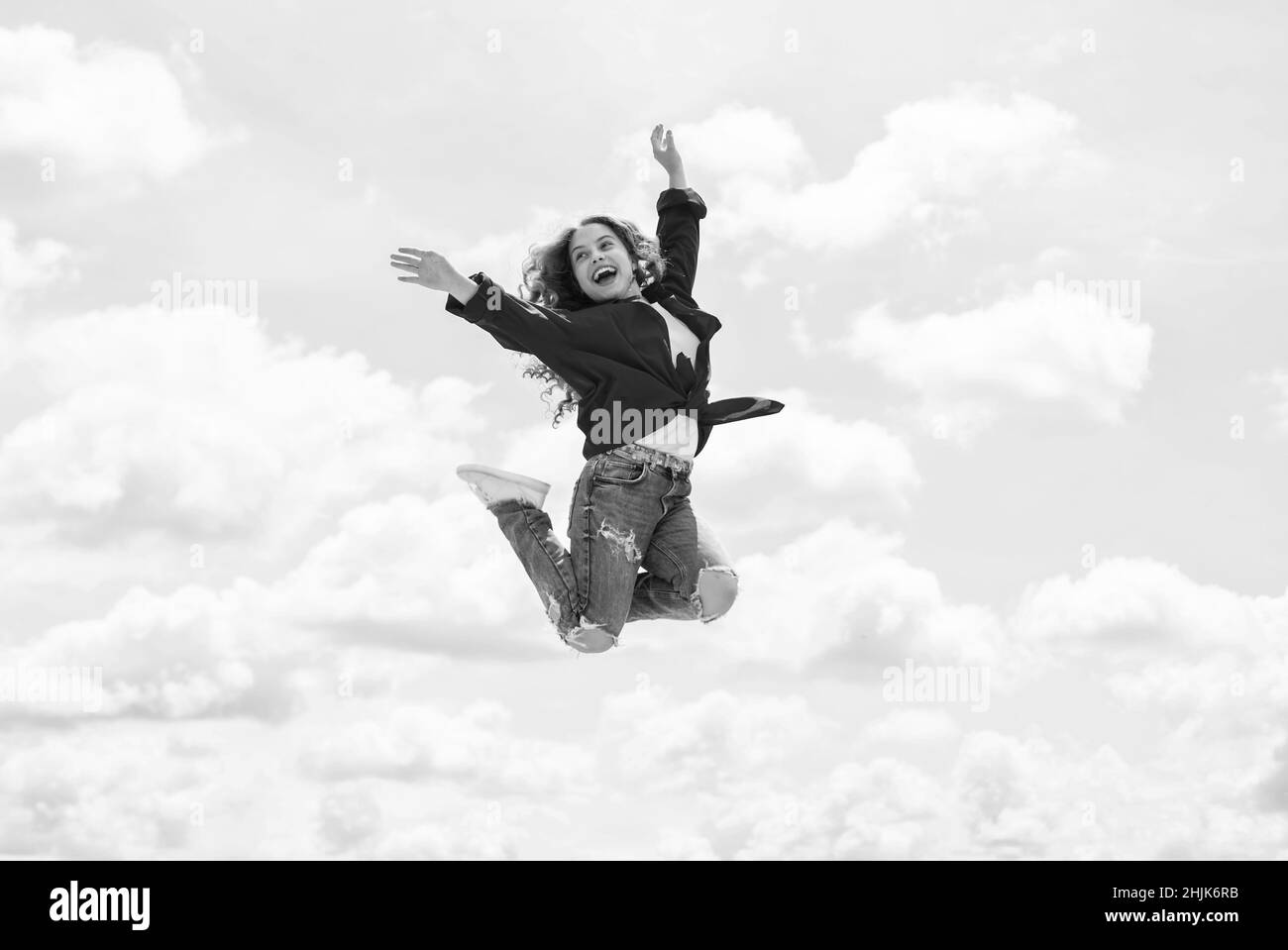 Happy Kid indossa una giacca rossa. Stile di vita e concetto di gente. Capretto primavera e caduta moda. Pieno di energia. Felicità di infanzia. Ragazza teen che salta alto in t Foto Stock