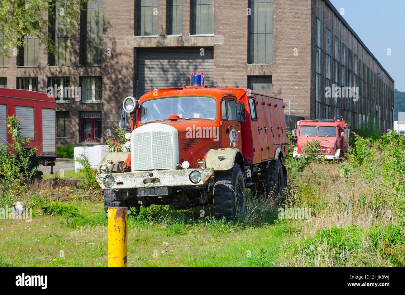 Vecchio camioncino abbandonato su un prato di fronte a un vecchio edificio di fabbrica. Foto Stock