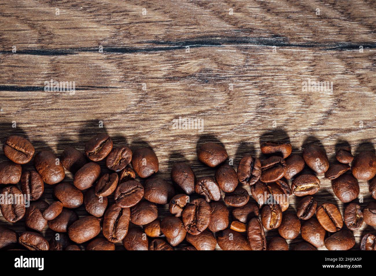 Chicchi di caffè arrostiti su tavola di legno marrone scuro con spazio copia. Vista dall'alto sui chicchi di caffè su sfondo di legno. Foto Stock