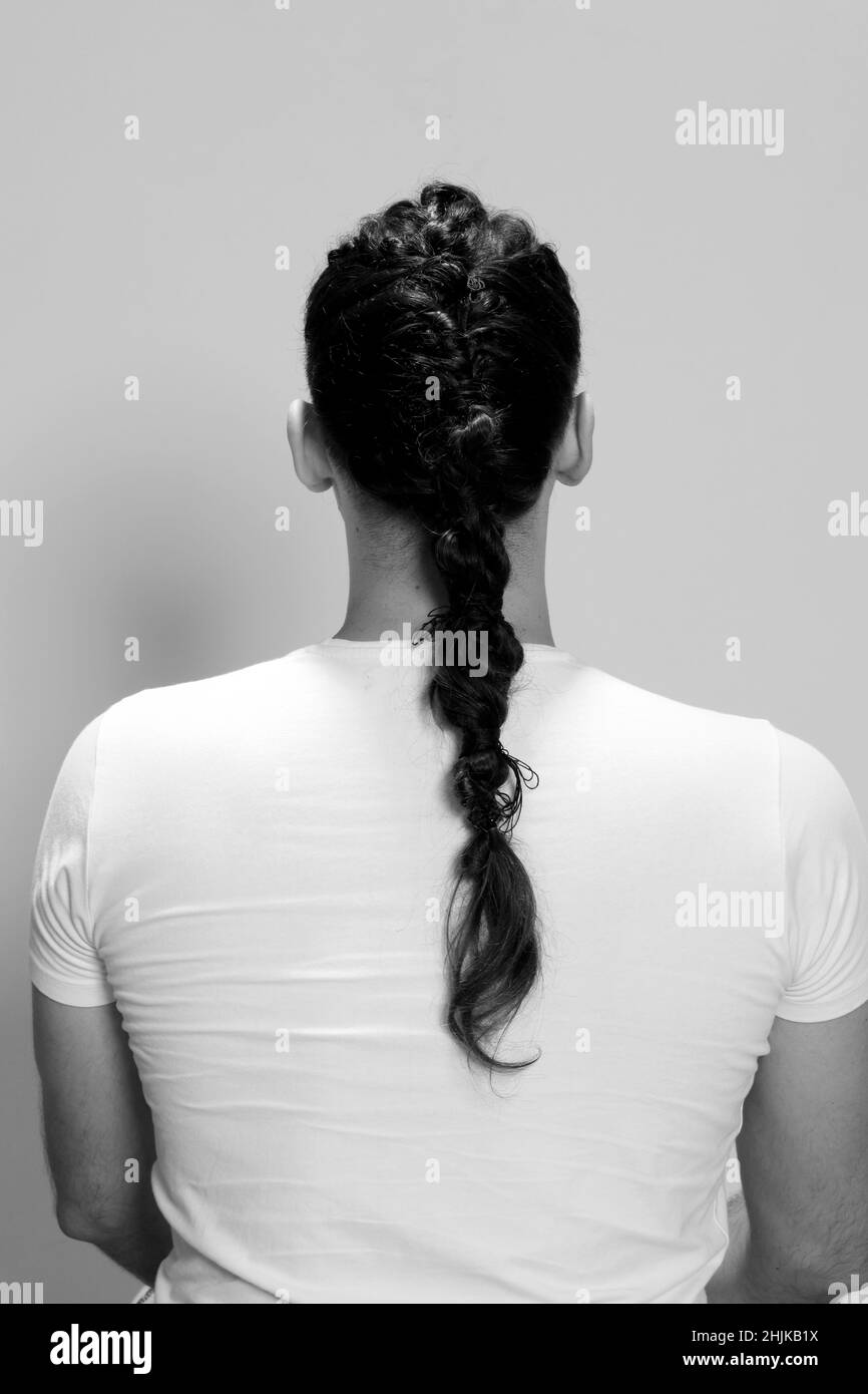 Modello maschile elegante con trecce in posa in studio su sfondo isolato. Stile, acconciatura, concetto di moda. Foto Stock