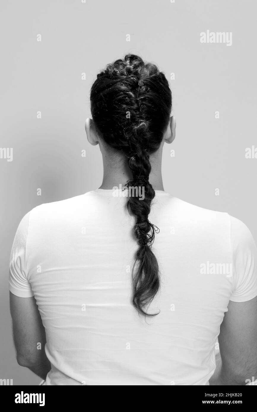 Modello maschile elegante con trecce in posa in studio su sfondo isolato. Stile, acconciatura, concetto di moda. Foto Stock