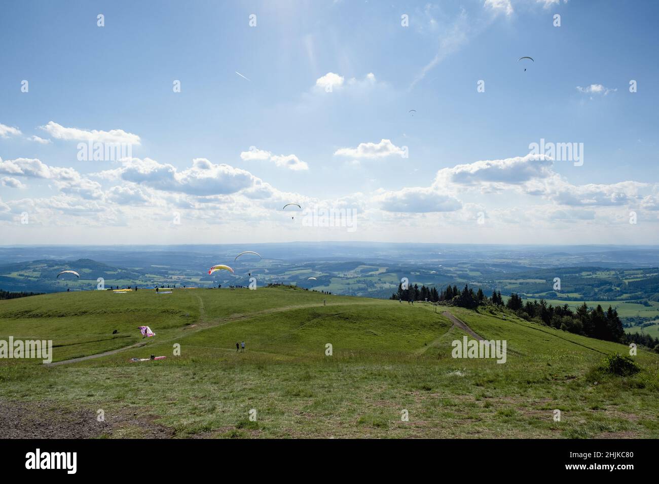 Vista dalla collina Wasserkuppe nel parco naturale Rhön della Germania con parapendio a terra e in aria. Foto Stock