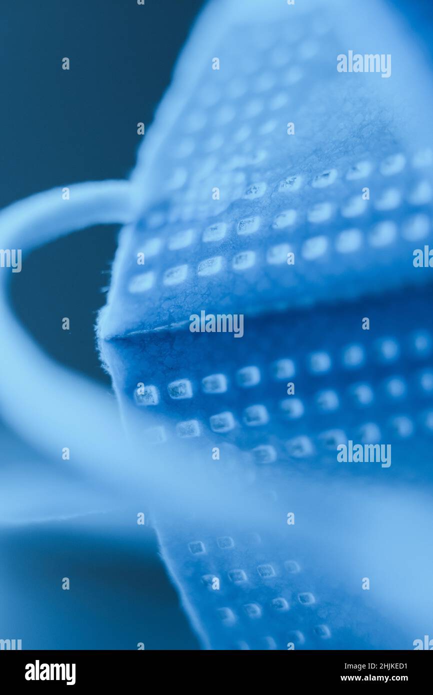 Composizione creativa astratta della maschera chirurgica in colori ultramarini profondi posti su una superficie riflettente. Foto Stock