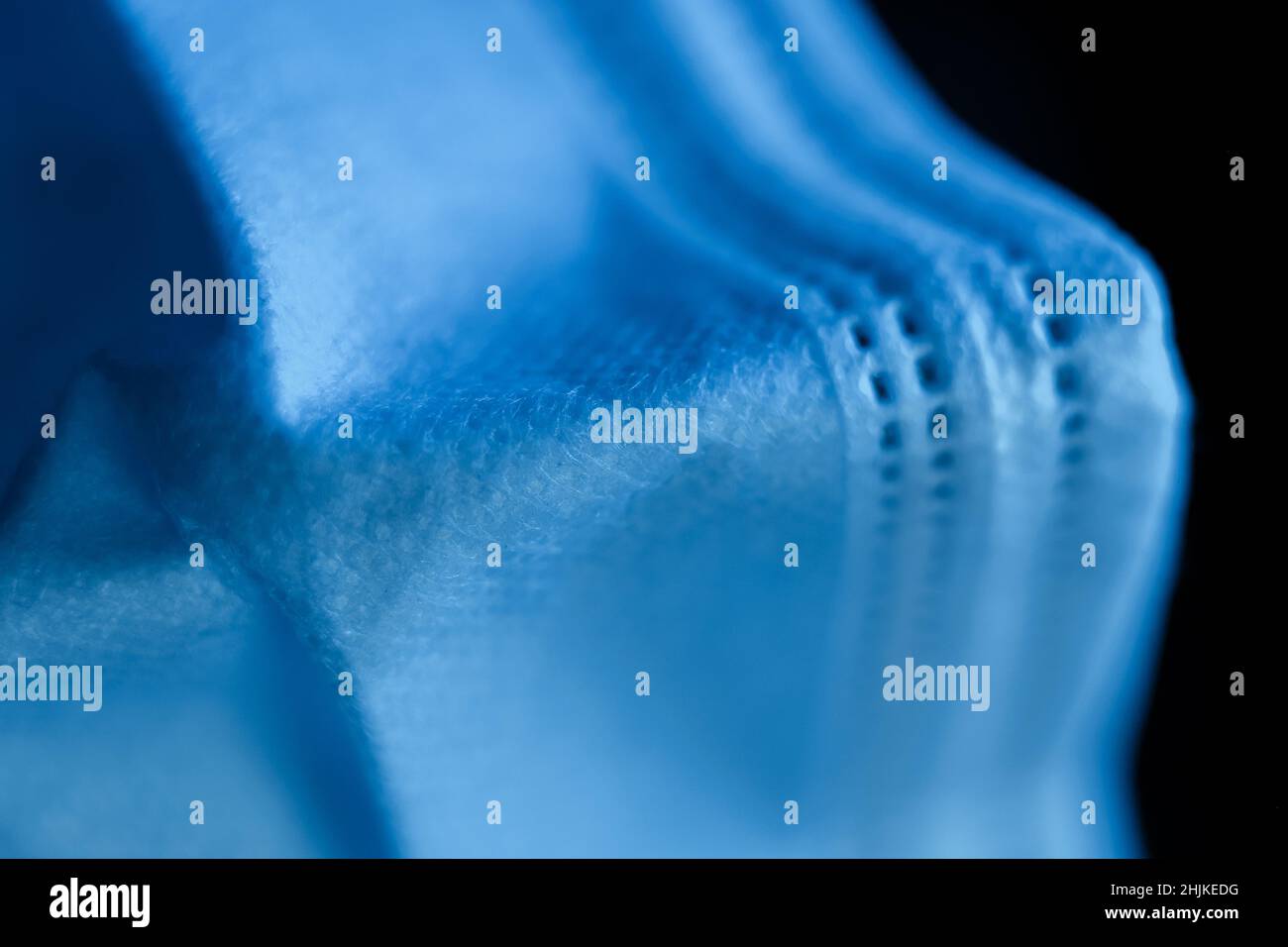 Maschera chirurgica in toni ultramarini profondi su sfondo scuro - macro shoot Foto Stock