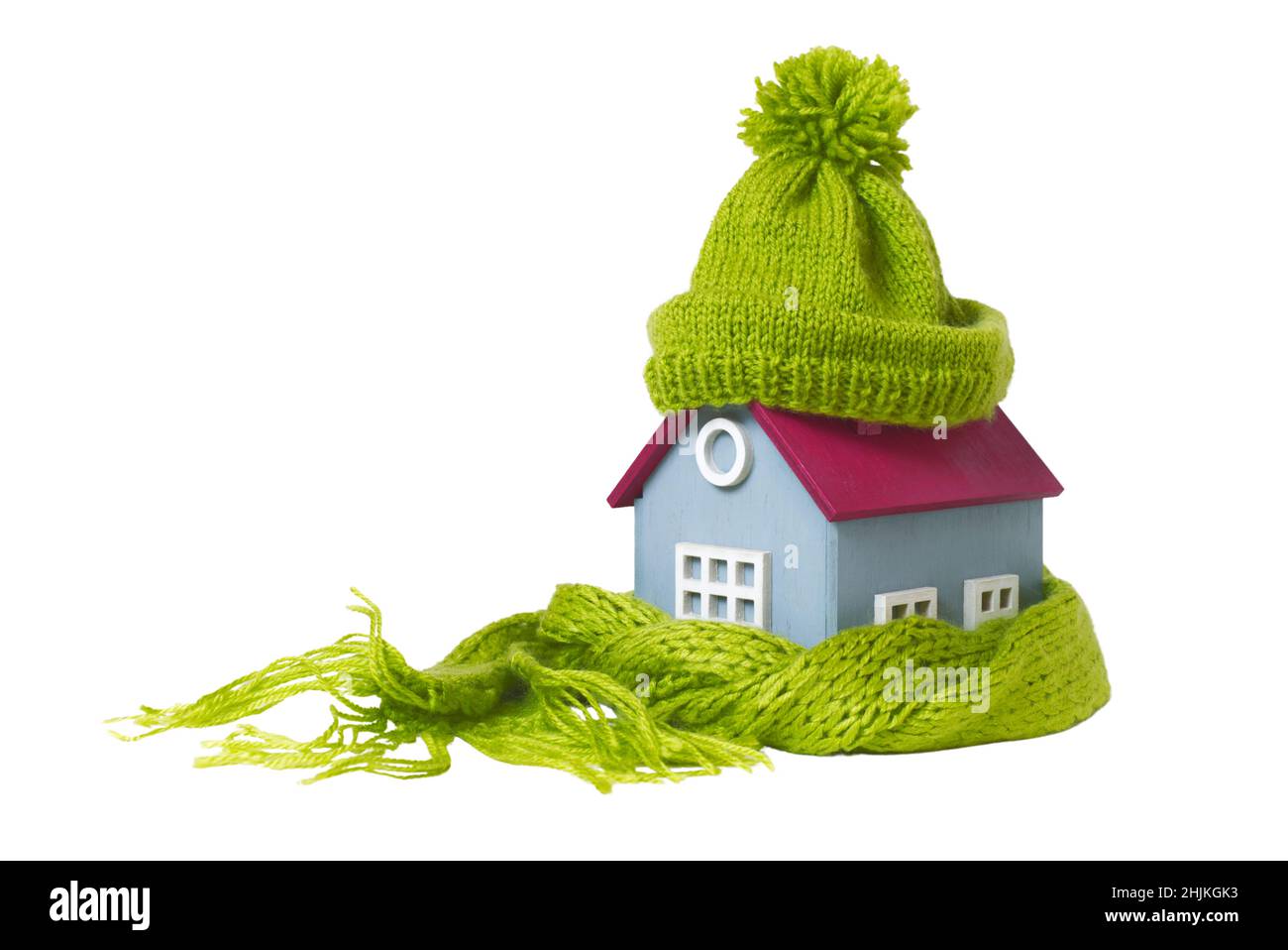 Casa modello concettuale in miniatura con cappello di lana verde e sciarpa, isolata su sfondo bianco Foto Stock