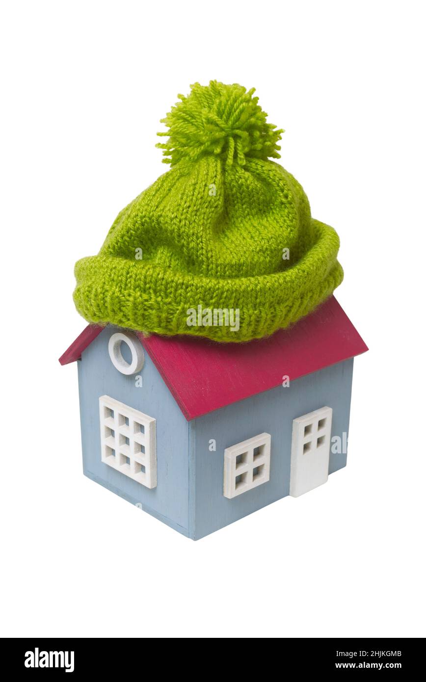 Casa modello concettuale in miniatura con cappello di lana verde, isolato su sfondo bianco Foto Stock