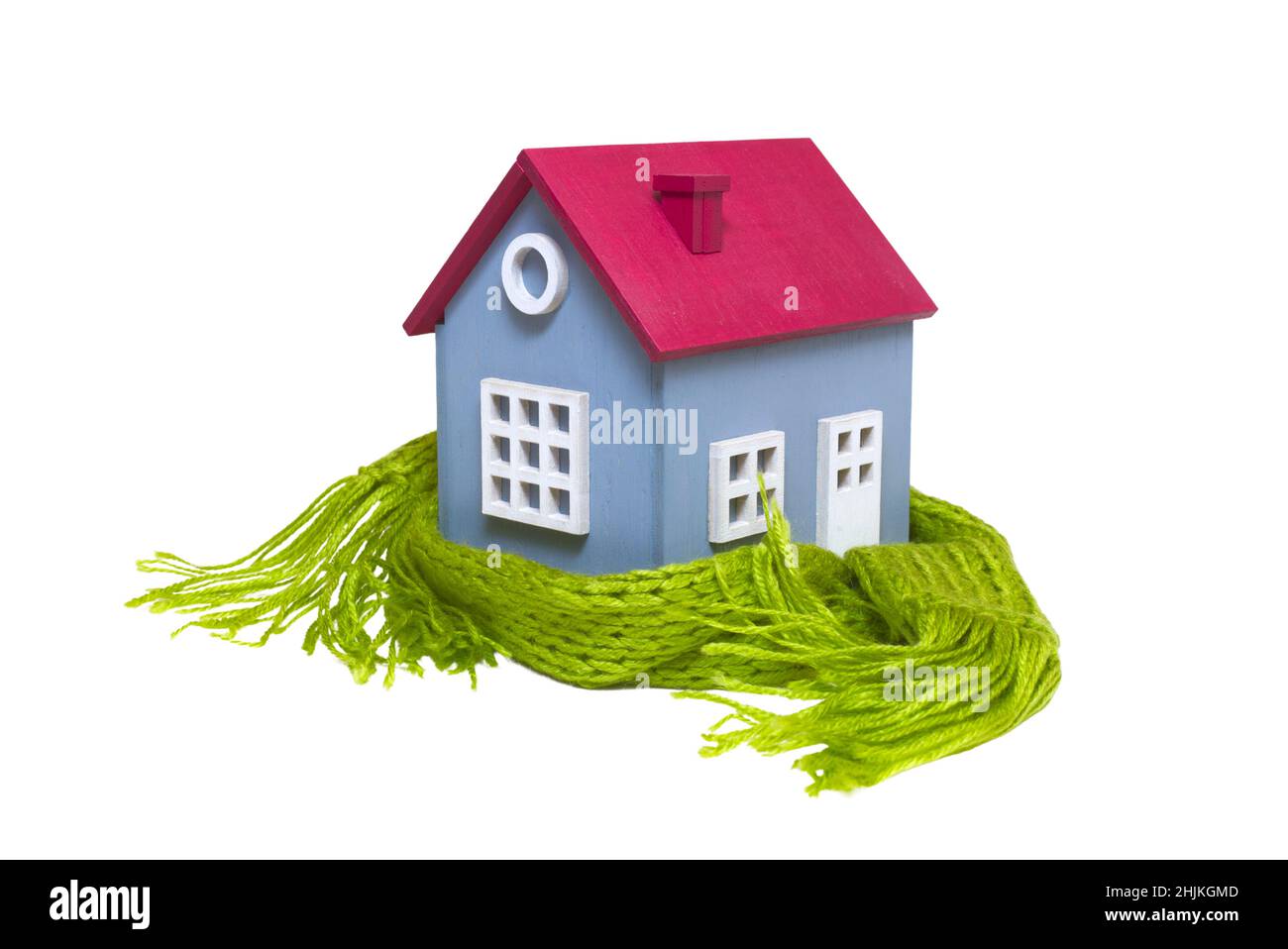 Casa modello concettuale in miniatura con sciarpa di lana verde, isolata su sfondo bianco Foto Stock