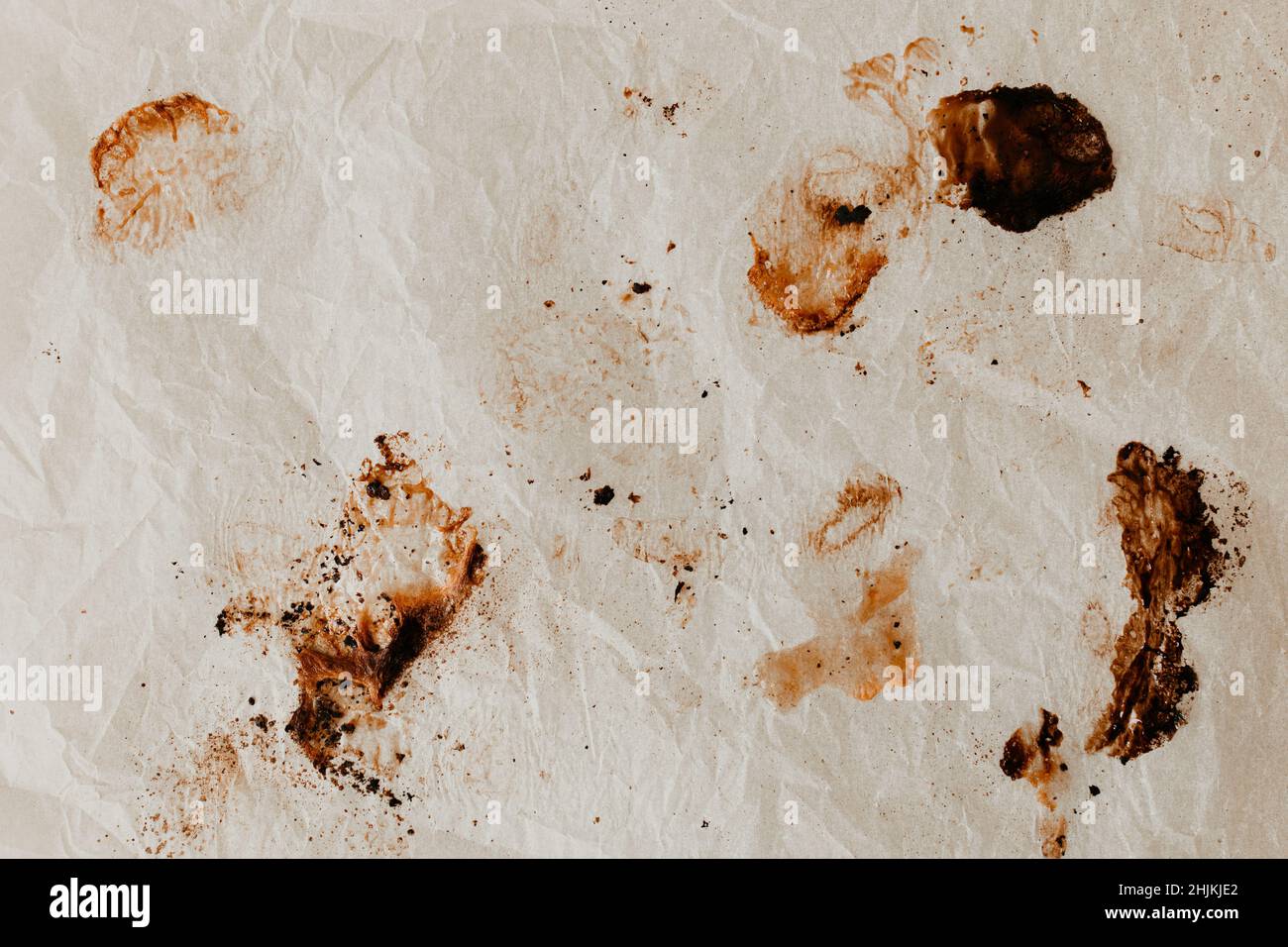Una carta da forno disordinata dopo aver fatto cuocere la patata dolce su di essa. Un sacco di dettagli astratti. Disposizione piatta, vista dall'alto. Macchie scure bruciate di zucchero caramellato. Foto Stock