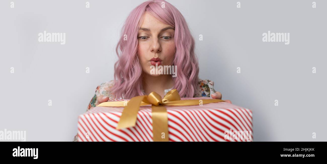 Ritratto di bella 20s donna che guarda la macchina fotografica e sorridente in posa con regalo attuale scatola isolato su uno sfondo grigio Foto Stock