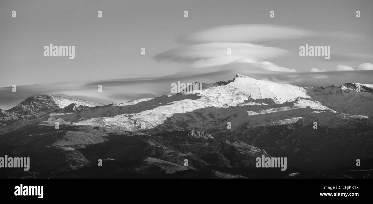 Spettacolari nuvole lenticolari sulle cime della Sierra Nevada (Spagna) al tramonto in inverno Foto Stock