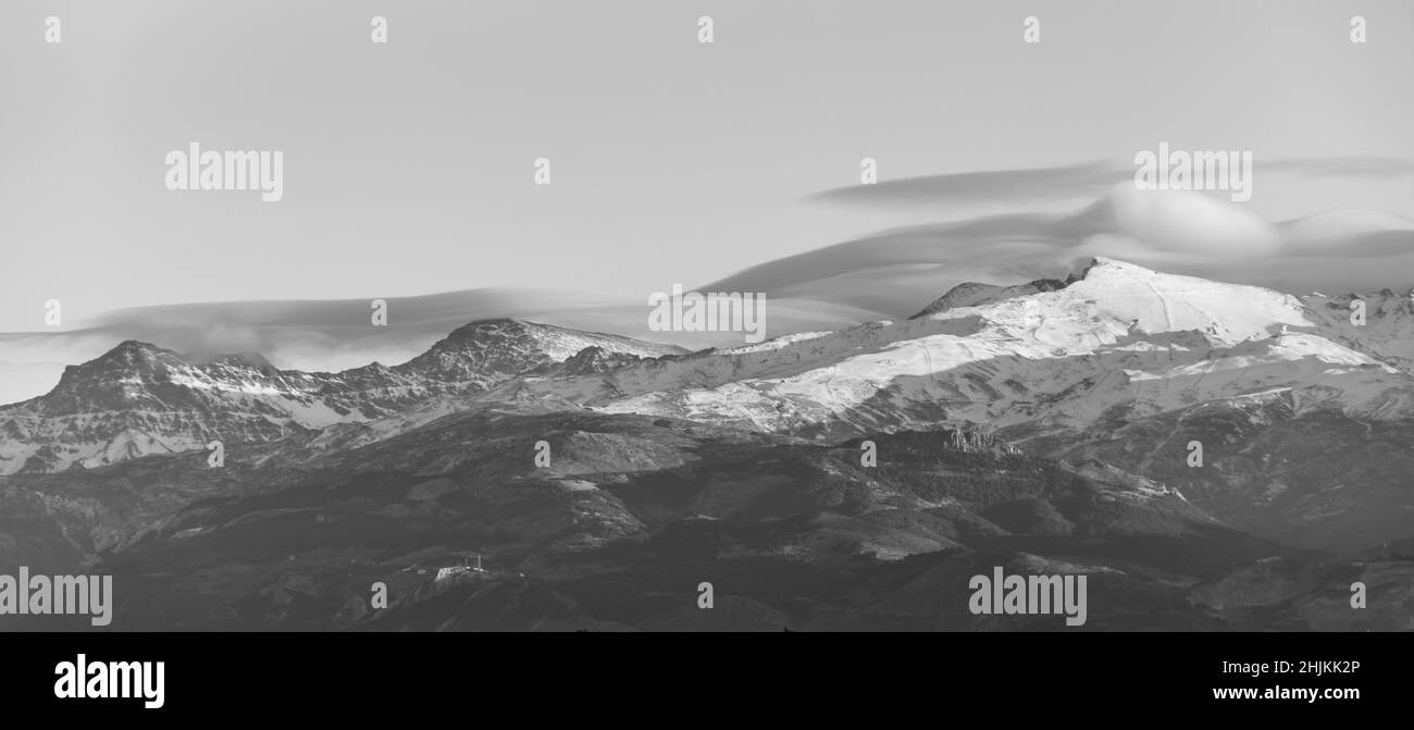 Spettacolari nuvole lenticolari sulle cime della Sierra Nevada (Spagna) al tramonto in inverno Foto Stock