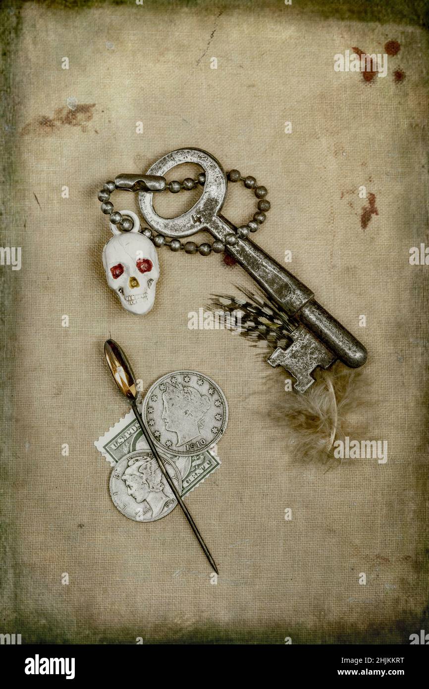 Chiave di scheletro su una catena di chiavi con piume, francobollo e perno a cappello poggiano in piano Foto Stock