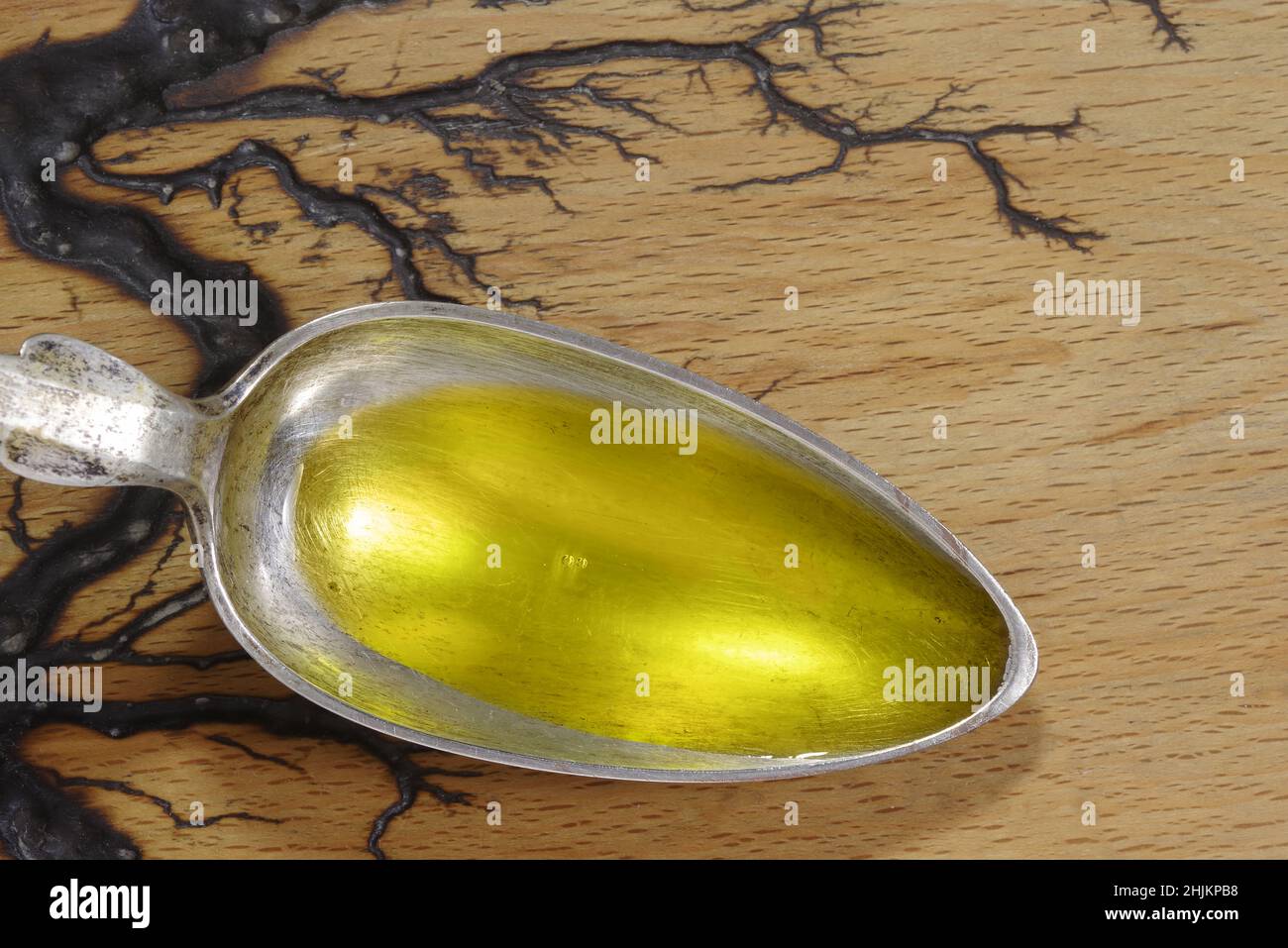 Versare l'olio di pesce in un cucchiaio di metallo su sfondo di legno. Omega 3 vitamine in primo piano cucchiaio Foto Stock