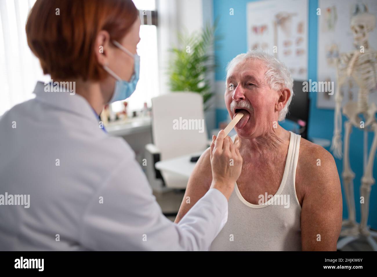 Medico femminile che controlla la gola dell'uomo anziano nel suo ufficio. Foto Stock