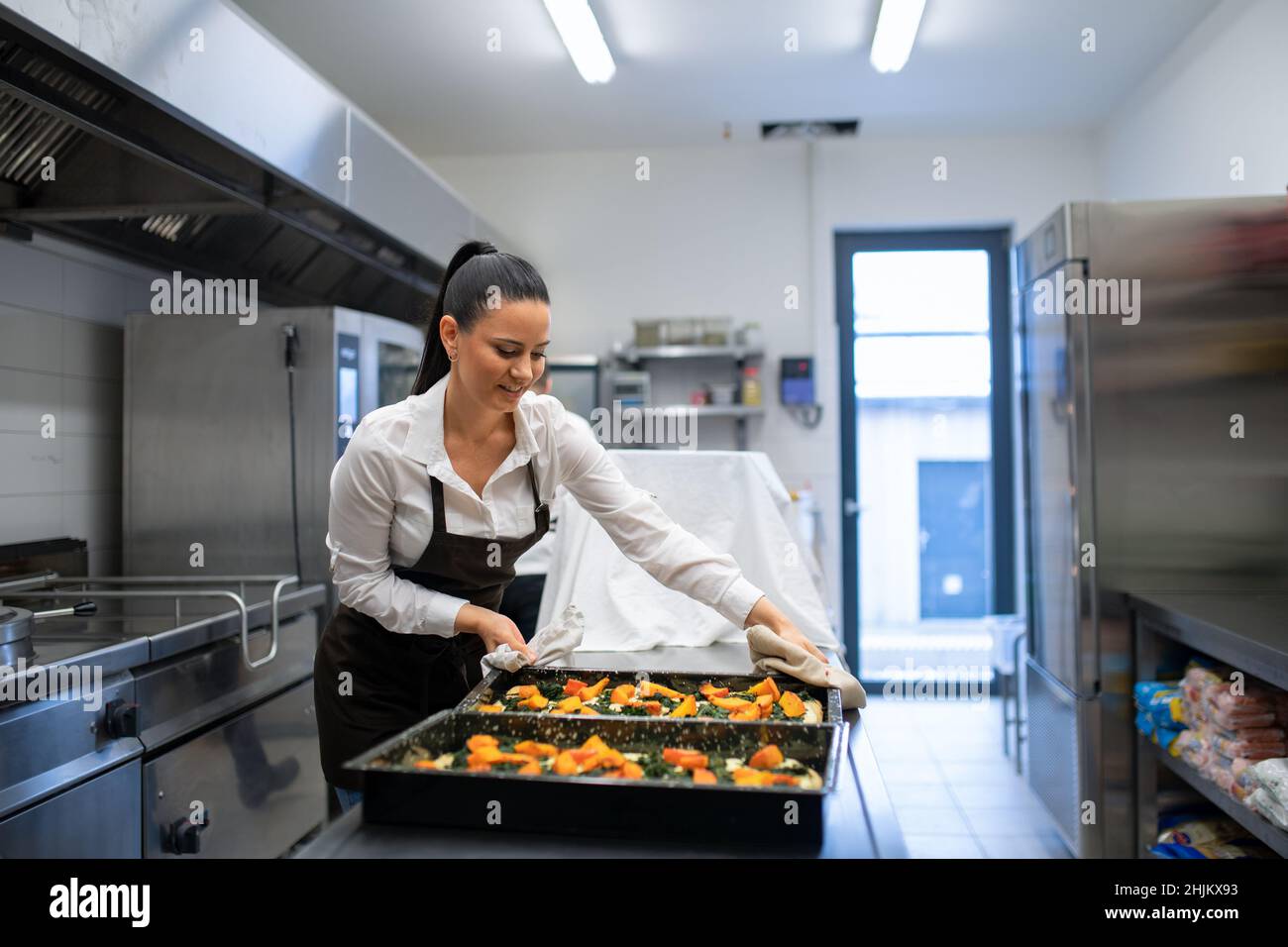 Chef professionista che lavora sui suoi piatti al chiuso nella cucina del ristorante. Foto Stock