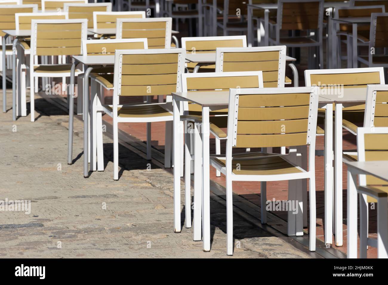 Tavoli di una terrazza disposti in fila con distanza di sicurezza Foto Stock