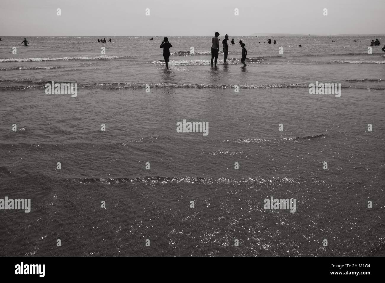 Sagome di persone che godono della bassa marea a West Wittering Beach, Regno Unito Foto Stock