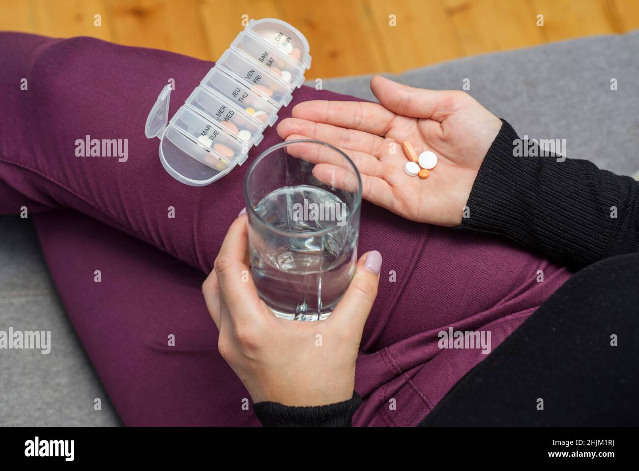 Una donna che sta per prendere le compresse dalla scatola della pillola. Una donna prende la medicina con un bicchiere d'acqua. Concetto di farmacia e assistenza sanitaria. Foto Stock