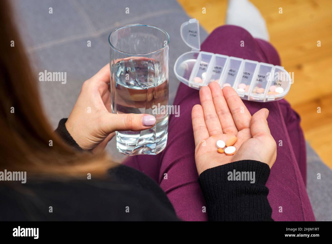 Una donna che sta per prendere le compresse dalla scatola della pillola. Una donna prende la medicina con un bicchiere d'acqua. Concetto di farmacia e assistenza sanitaria. Foto Stock