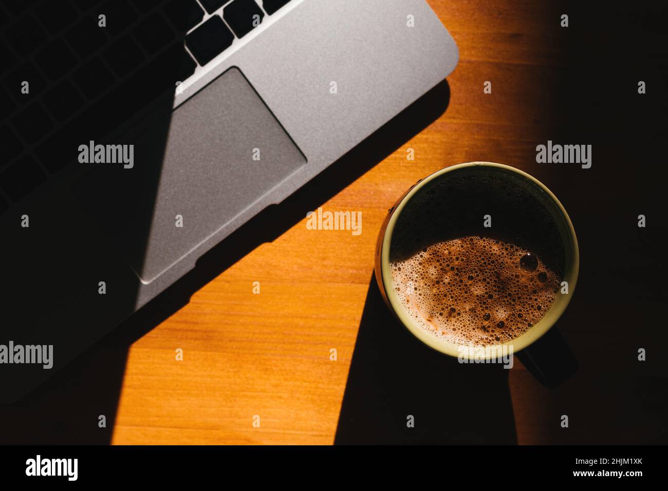 Pausa caffè in ufficio, computer portatile e tazza di caffè sulla scrivania, vista dall'alto con focus selettivo Foto Stock