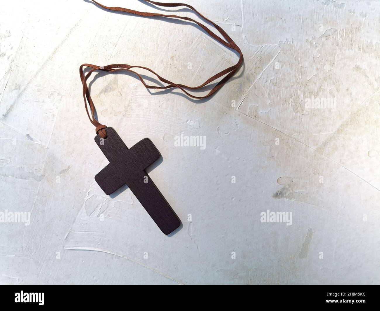 Una croce cristiana in legno su sfondo bianco vecchio. Concetto di cristianesimo. Disposizione piatta. Spazio di copia. Foto Stock