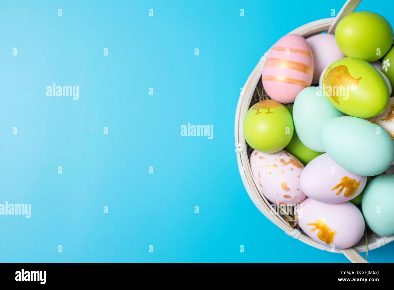 Cestino di Pasqua pieno di uova di Pasqua dipinte su sfondo blu. Colorate uova di pasqua dipinte in cestino su sfondo blu. Foto Stock