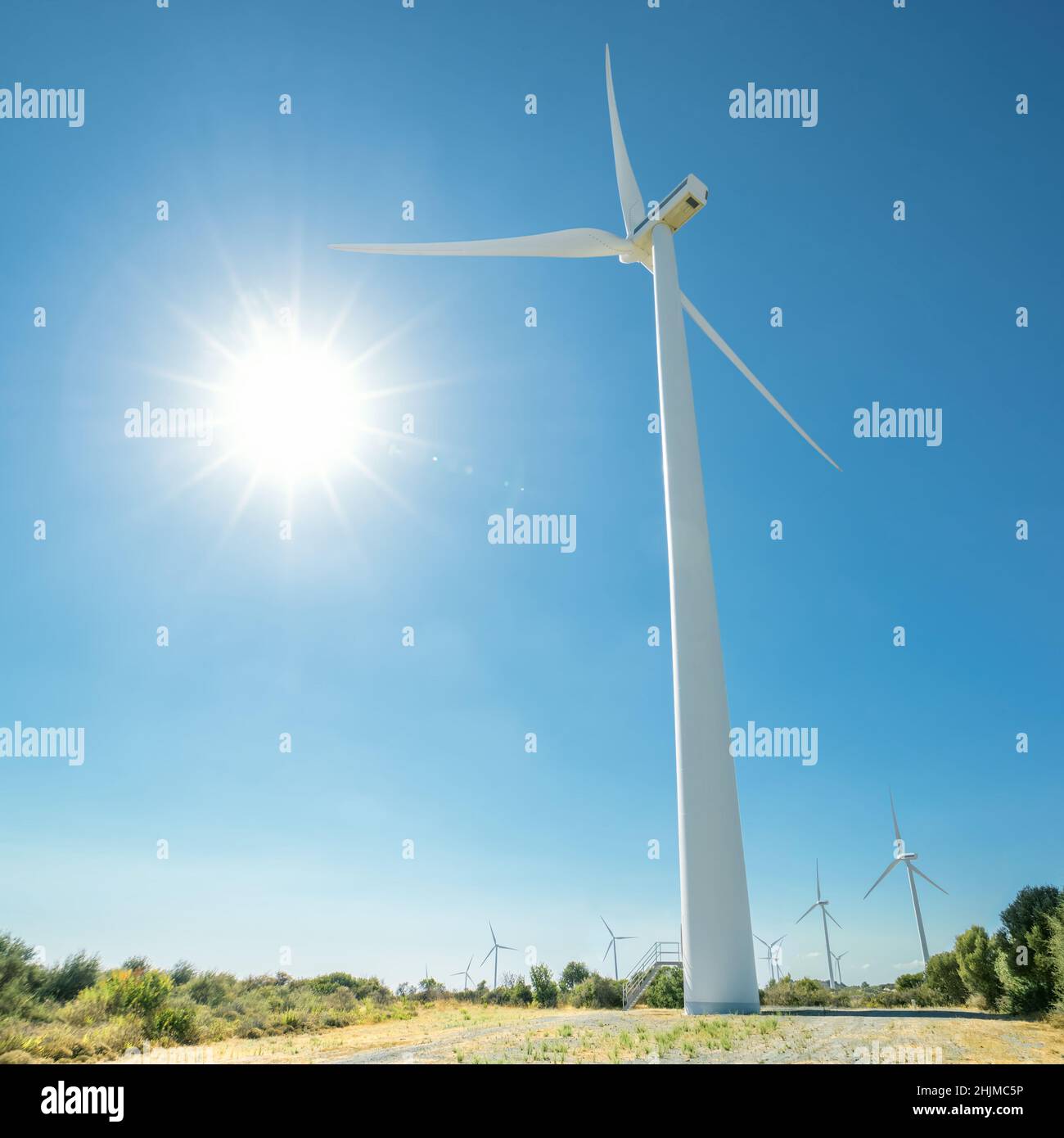 Enorme generatore di vento contro il sole splendente e il cielo blu. Allevamento eolico di Oreites a Cipro Foto Stock