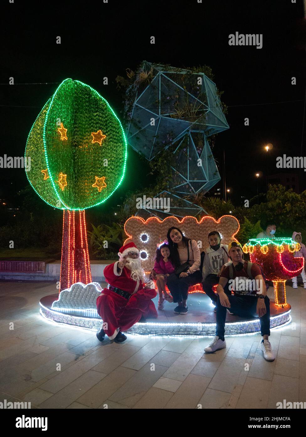 Medellin, Antioquia, Colombia - Gennaio 4 2022: Famiglia in posa con decorazioni natalizie e Babbo Natale in serata Foto Stock