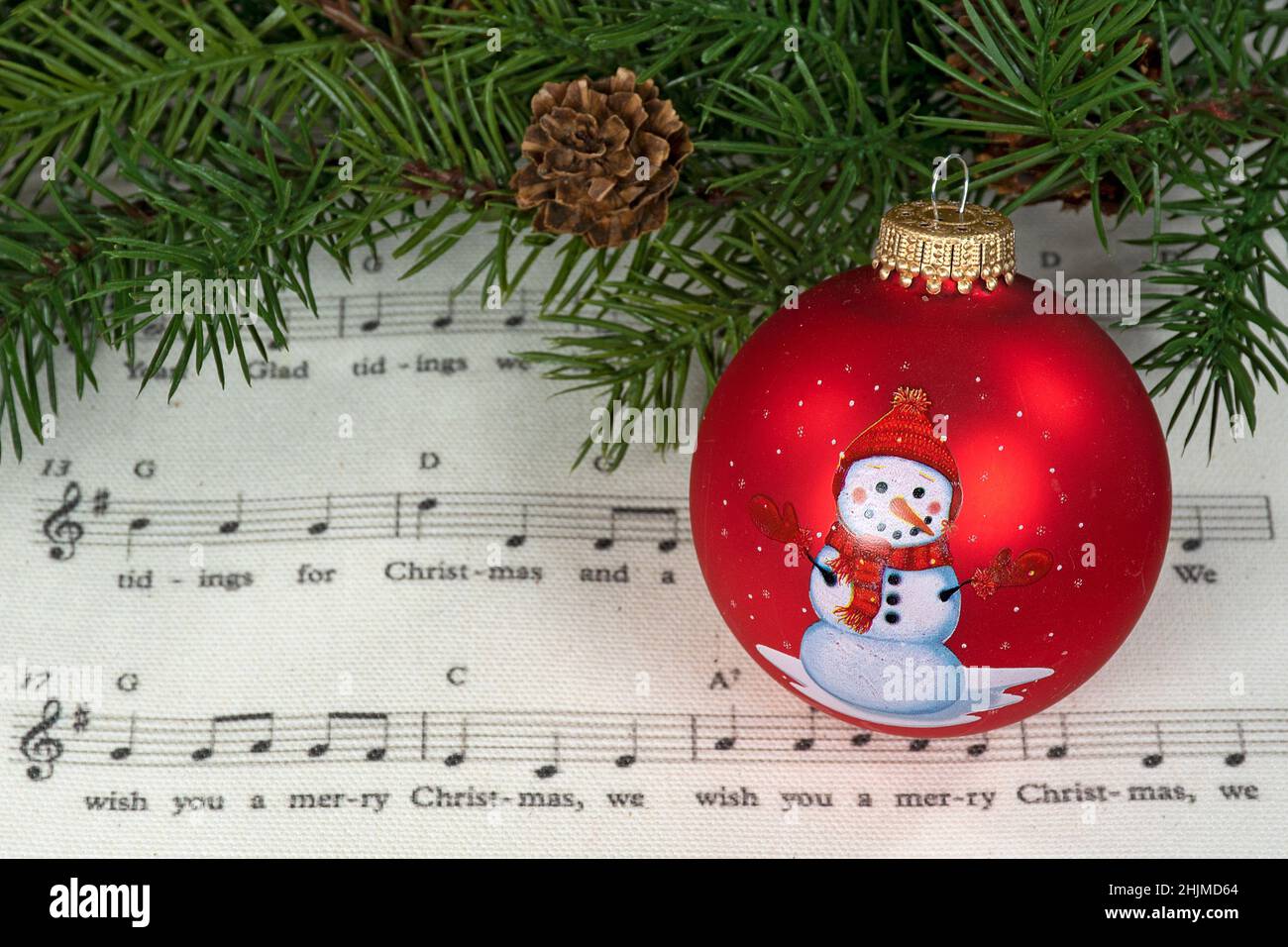 Ornamento rosso di Natale con pupazzo di neve sulla musica di festa con tosse di pino verde Foto Stock