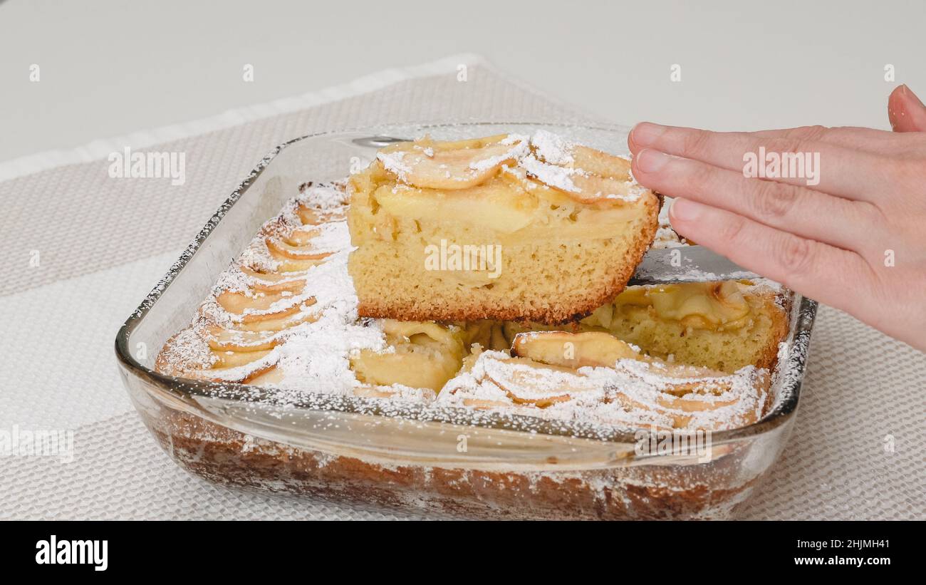Donna che serve torta di mele. Torta di mele appena sfornata con biscotto a base e mele a fette che si tagliano da vicino in un recipiente di vetro Foto Stock