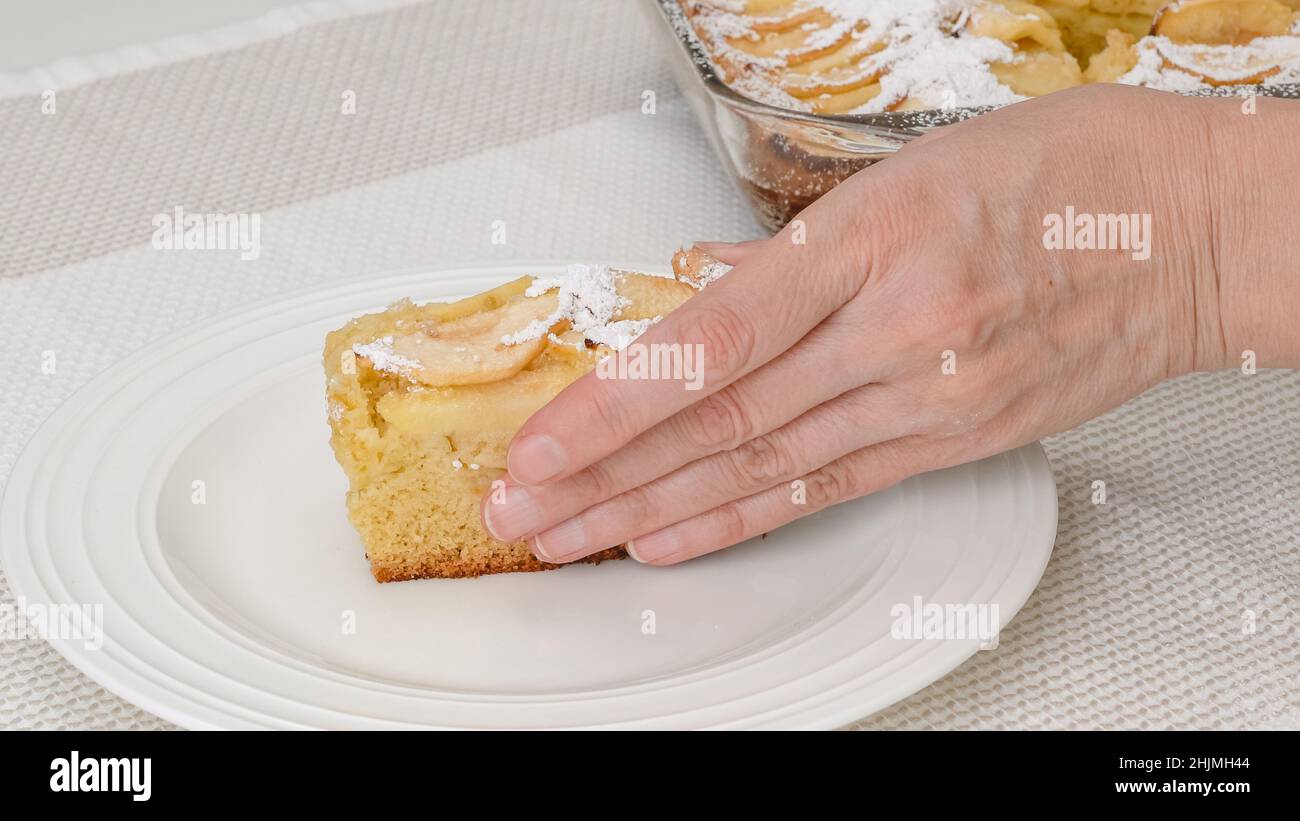 Donna che serve torta di mele. Torta di mele appena sfornata con biscotto a base e mele affettate, con un piatto a vista Foto Stock