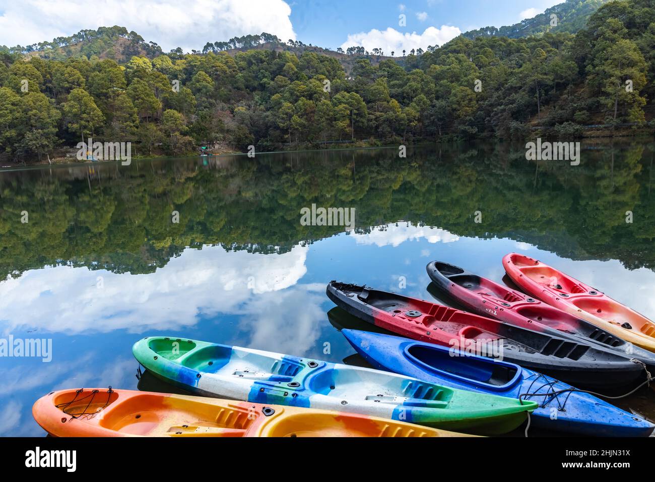 Barche colorate sulla riva di un lago con il riflesso del cielo e delle colline Foto Stock
