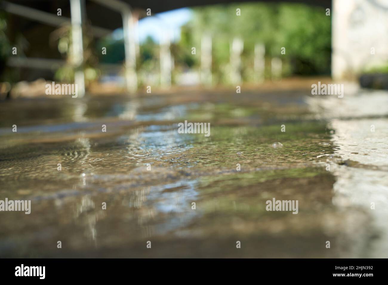 Acqua sporca in caso di allagamento sotto un ponte. Ringhiera nella sfocatura profonda. Foto Stock