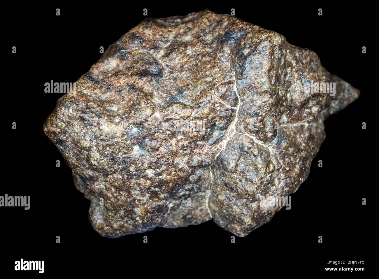 Pietra meteorite condrite isolata su sfondo nero. Pezzo di roccia formato durante la creazione del sistema solare. Foto Stock