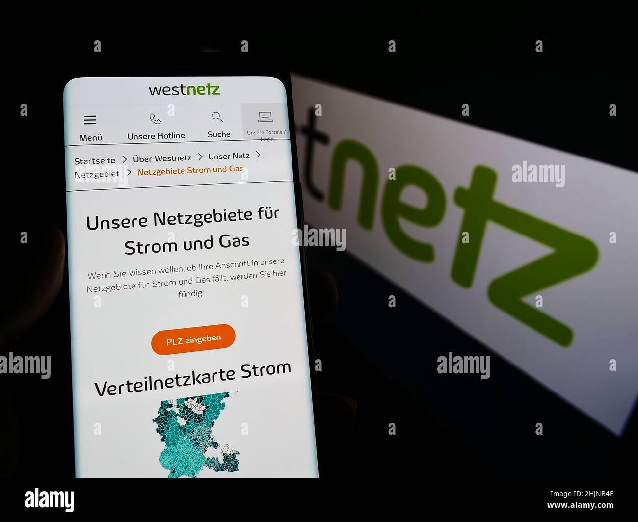 Persona che detiene il cellulare con il sito web della società tedesca Westnetz GmbH sullo schermo di fronte al logo aziendale. Concentrarsi sul centro del display del telefono. Foto Stock