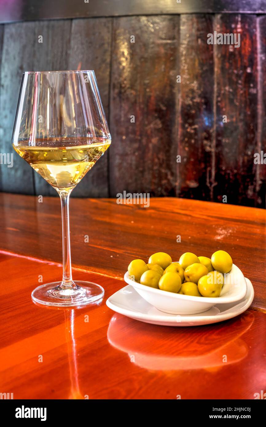 Bicchiere di vino bianco e olive servito in un tapas bar di Valencia, Spagna Foto Stock