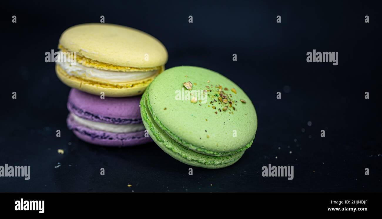 Macaron o macaron francesi dolci e colorati su sfondo nero. Foto Stock