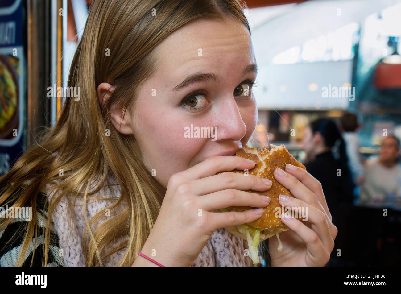 Ragazza adolescente che mangia hamburger. Fast food. Foto Stock