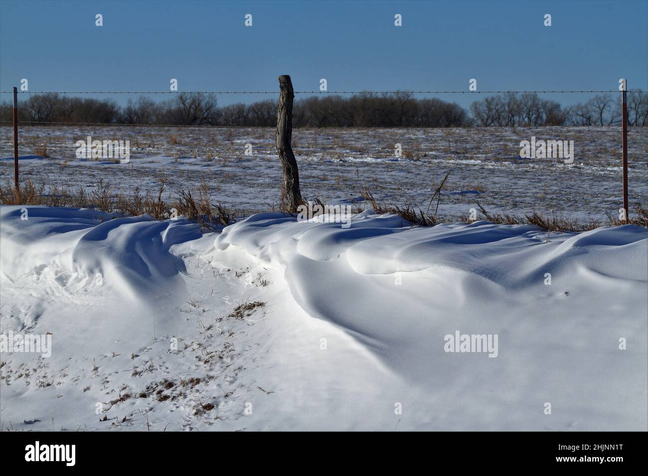 Neve Drift con una recinzione e campo fuori nel paese Foto Stock