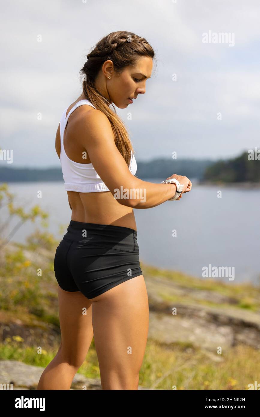 Ritratto di donna in forma utilizzando il dispositivo di orologio fitness smart sotto l'allenamento Foto Stock