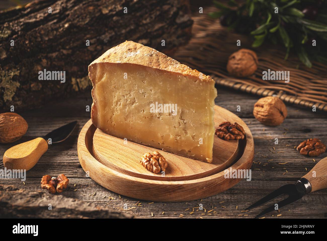 Ancora vita di una fetta triangolare di vecchio formaggio duro sul tagliere di legno Foto Stock